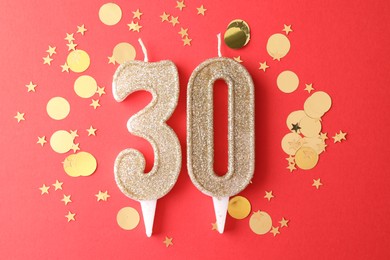 Photo of 30th birthday. Number shaped candles and confetti on red background, flat lay