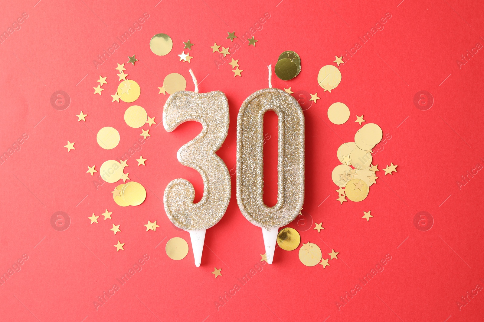 Photo of 30th birthday. Number shaped candles and confetti on red background, flat lay