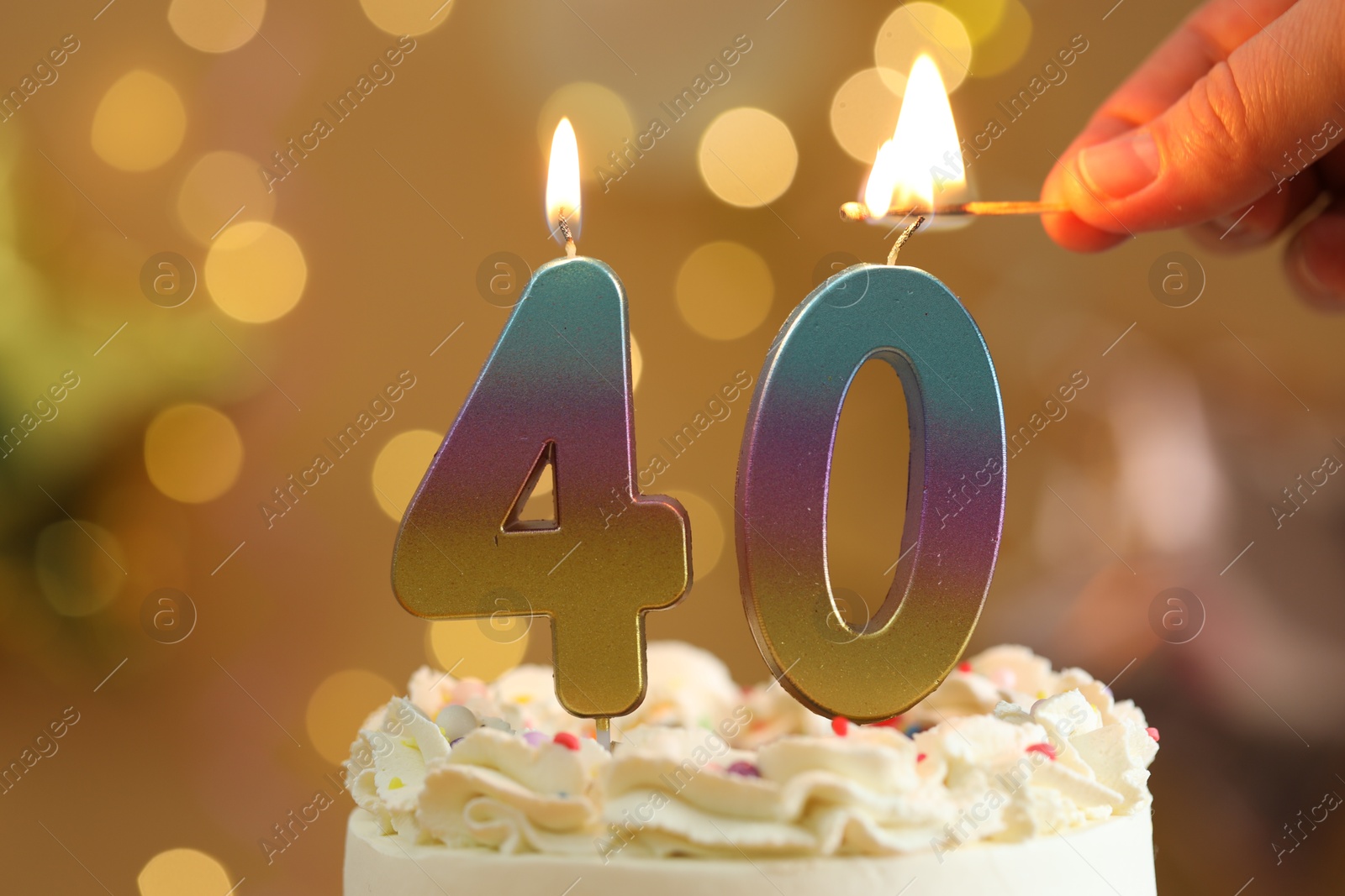 Photo of 40th birthday. Woman lighting number shaped candles on cake against blurred lights, closeup. Bokeh effect