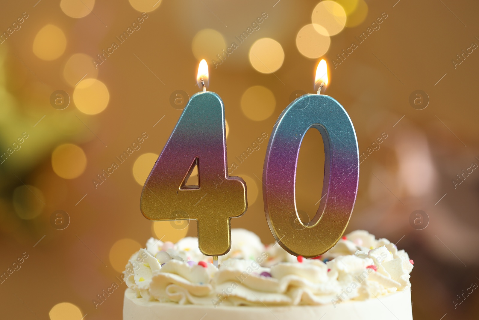 Photo of 40th birthday. Burning number shaped candles on cake against blurred background with lights, closeup. Bokeh effect