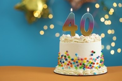 Photo of 40th birthday. Cake with burning number shaped candles on table against blurred background with lights, closeup and space for text. Bokeh effect