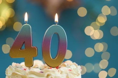 Photo of 40th birthday. Burning number shaped candles on cake against blurred background with lights, closeup and space for text. Bokeh effect