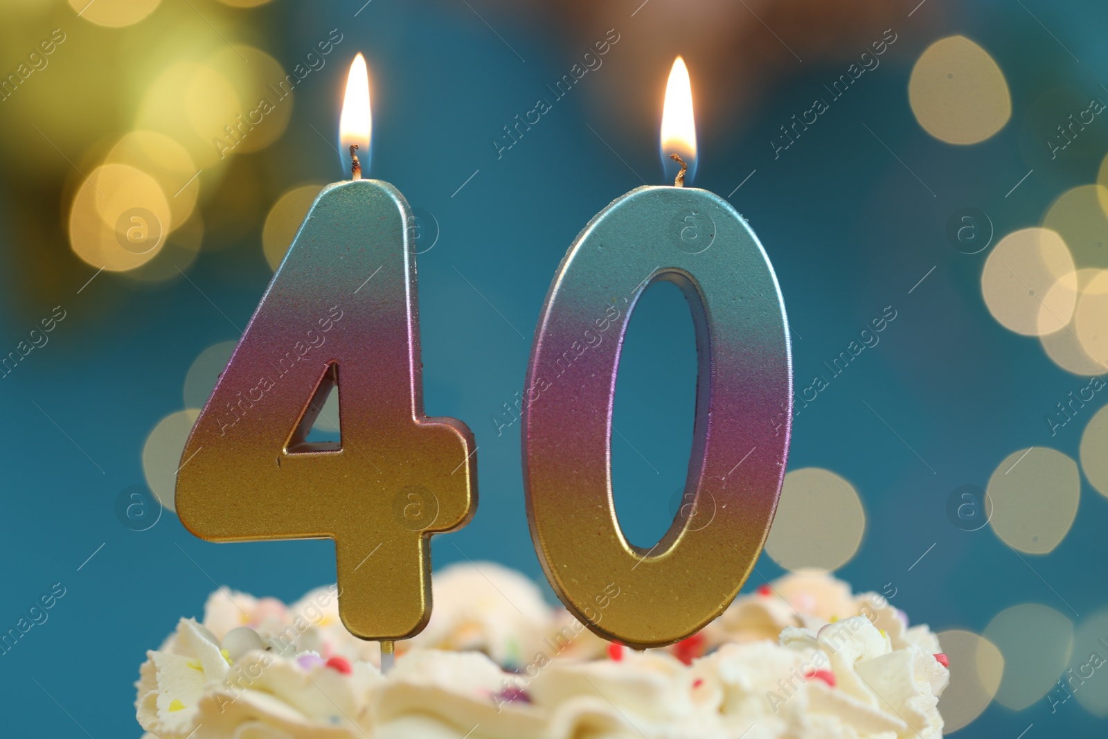 Photo of 40th birthday. Burning number shaped candles on cake against blurred background with lights, closeup. Bokeh effect