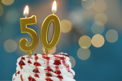 Photo of 50th birthday. Burning number shaped candles on cupcake against blurred background with lights, closeup and space for text. Bokeh effect