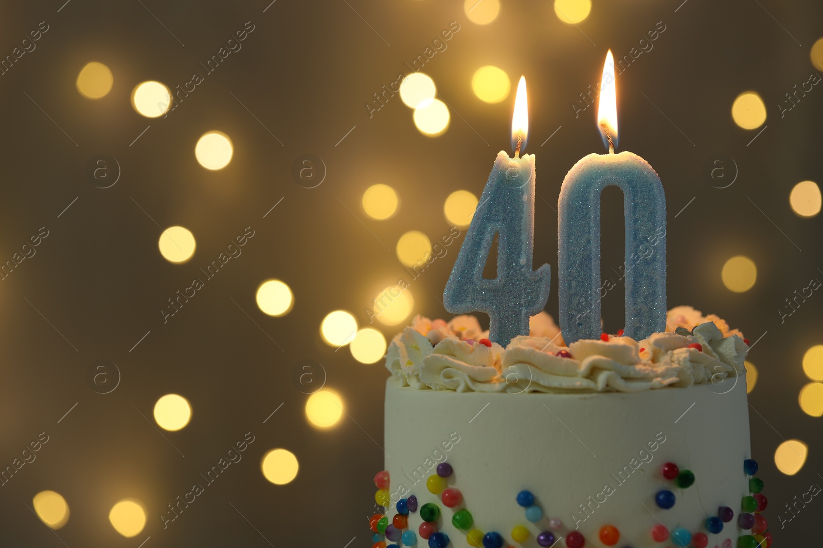 Photo of 40th birthday. Burning number shaped candles on cake against blurred background with lights, closeup and space for text. Bokeh effect