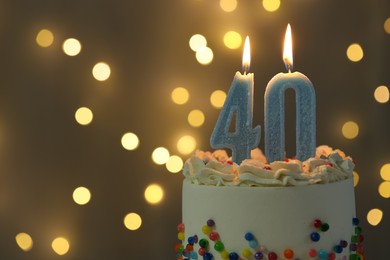 Photo of 40th birthday. Burning number shaped candles on cake against blurred background with lights, closeup and space for text. Bokeh effect