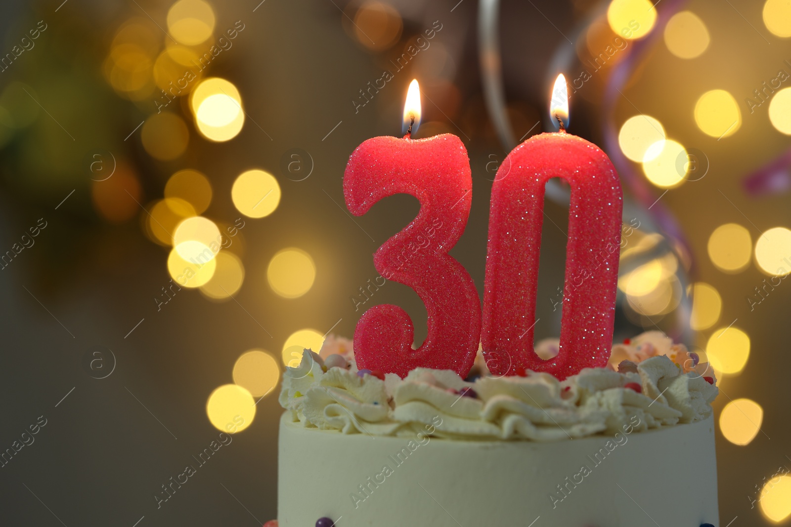 Photo of 30th birthday. Burning number shaped candles on cake against blurred background with lights, closeup and space for text. Bokeh effect