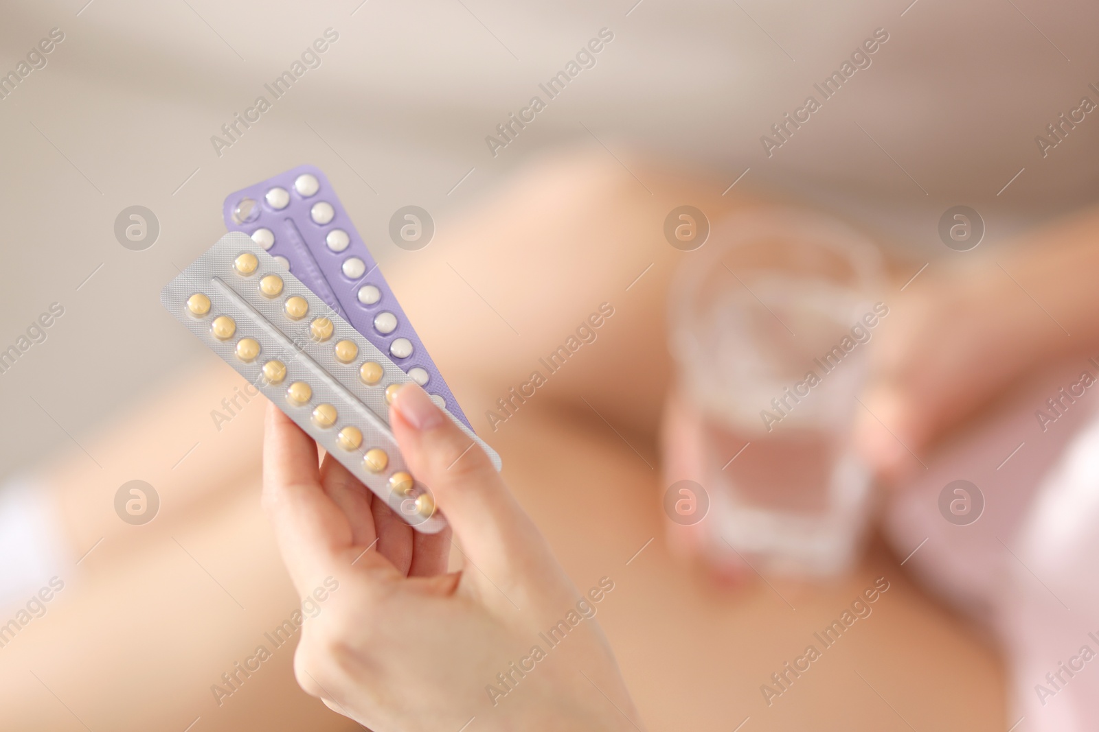 Photo of Woman with blisters of contraceptive pills indoors, closeup