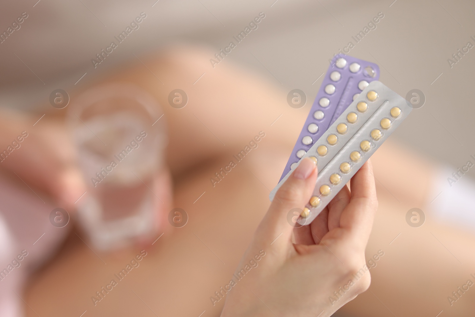 Photo of Woman with blisters of contraceptive pills indoors, closeup