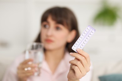 Photo of Woman with blister of contraceptive pills indoors, selective focus