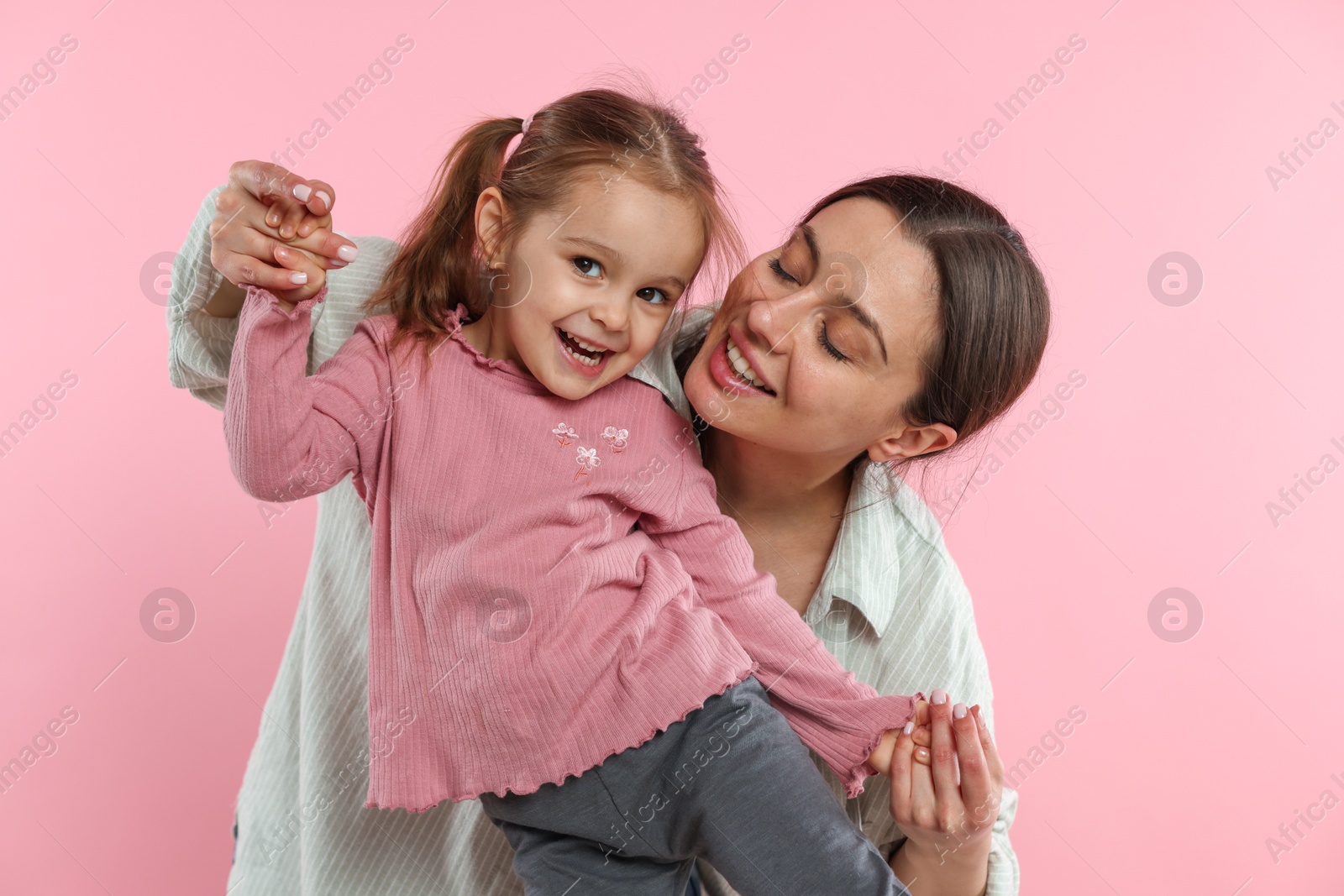 Photo of Family portrait of beautiful mother with little daughter on pink background