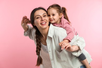 Photo of Portrait of happy mother and her cute daughter on pink background