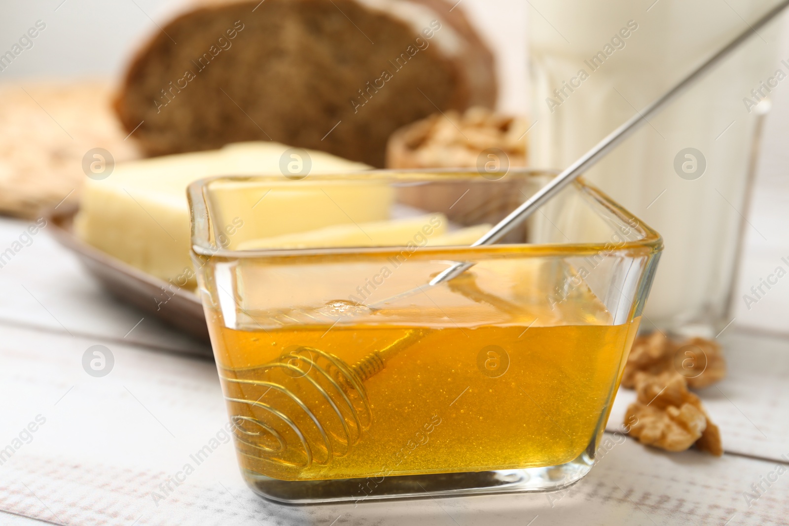 Photo of Sweet honey on white wooden table, closeup