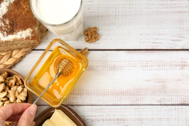 Photo of Woman taking honey with dipper at white wooden table, top view. Space for text