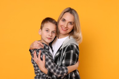 Photo of Mother and son hugging on orange background