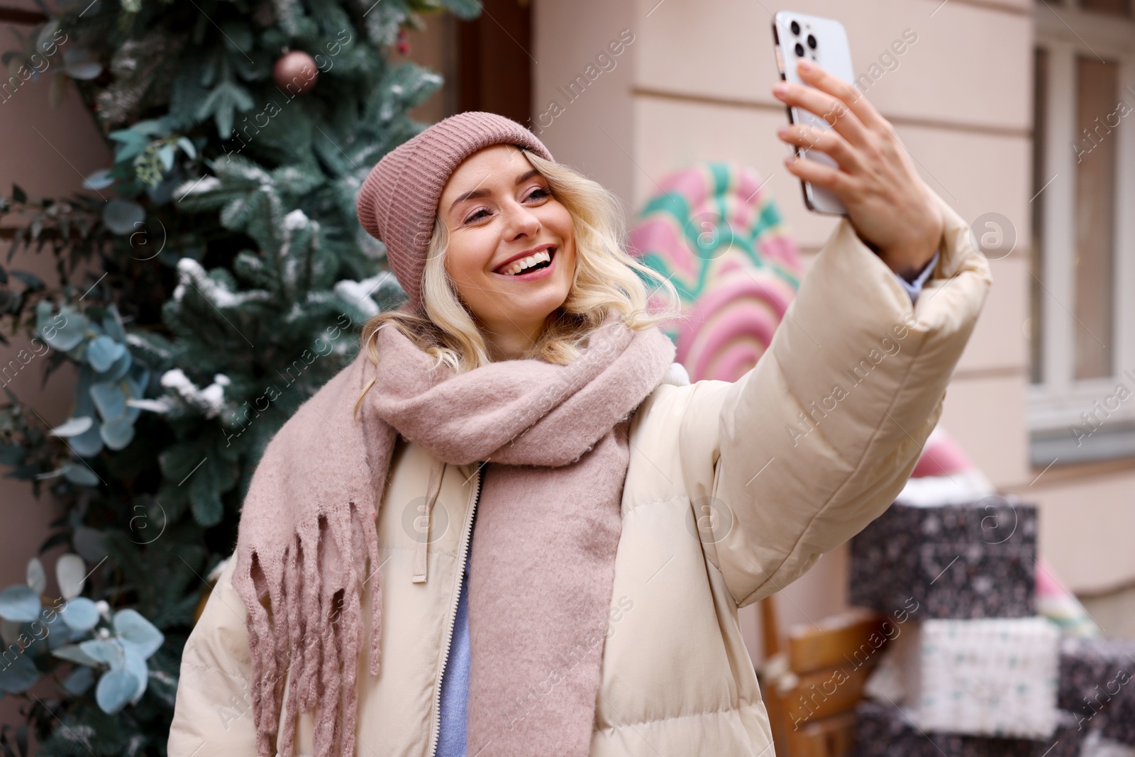 Photo of Happy woman taking selfie on city street. Christmas season