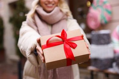 Photo of Woman with Christmas gift on city street, closeup