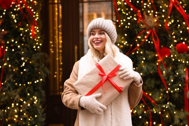 Photo of Happy woman with Christmas gift on city street