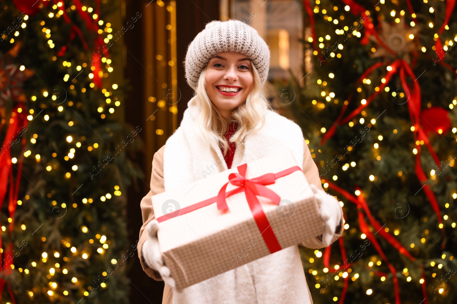 Photo of Happy woman with Christmas gift on city street