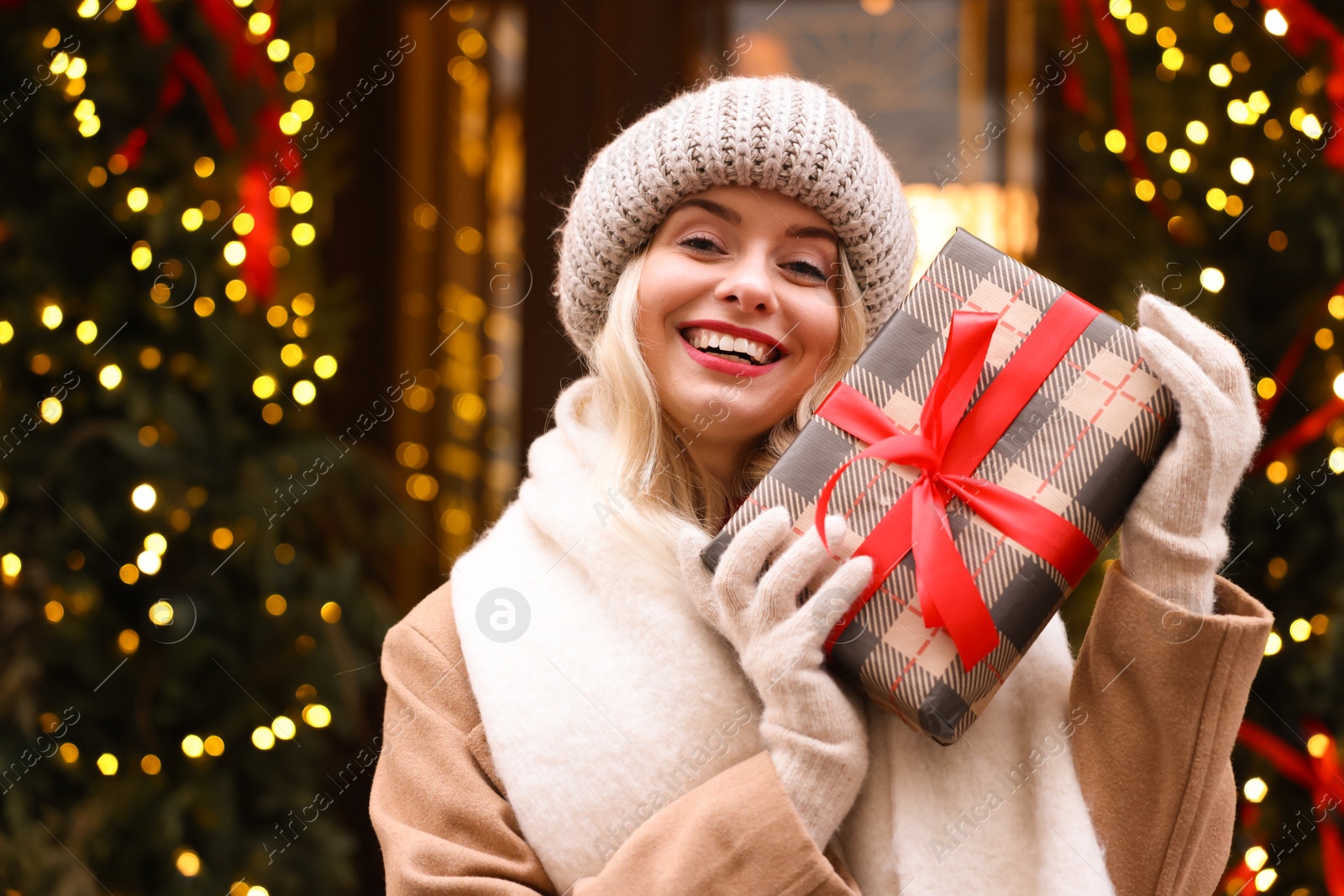 Photo of Happy woman with Christmas gift on city street, space for text