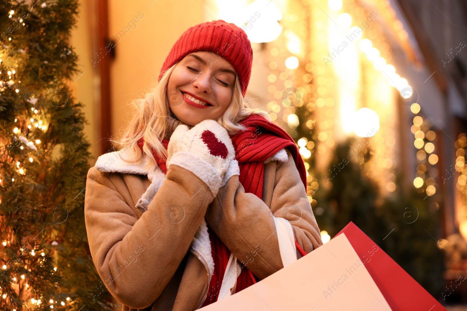 Photo of Happy woman with shopping bags on city street. Christmas season