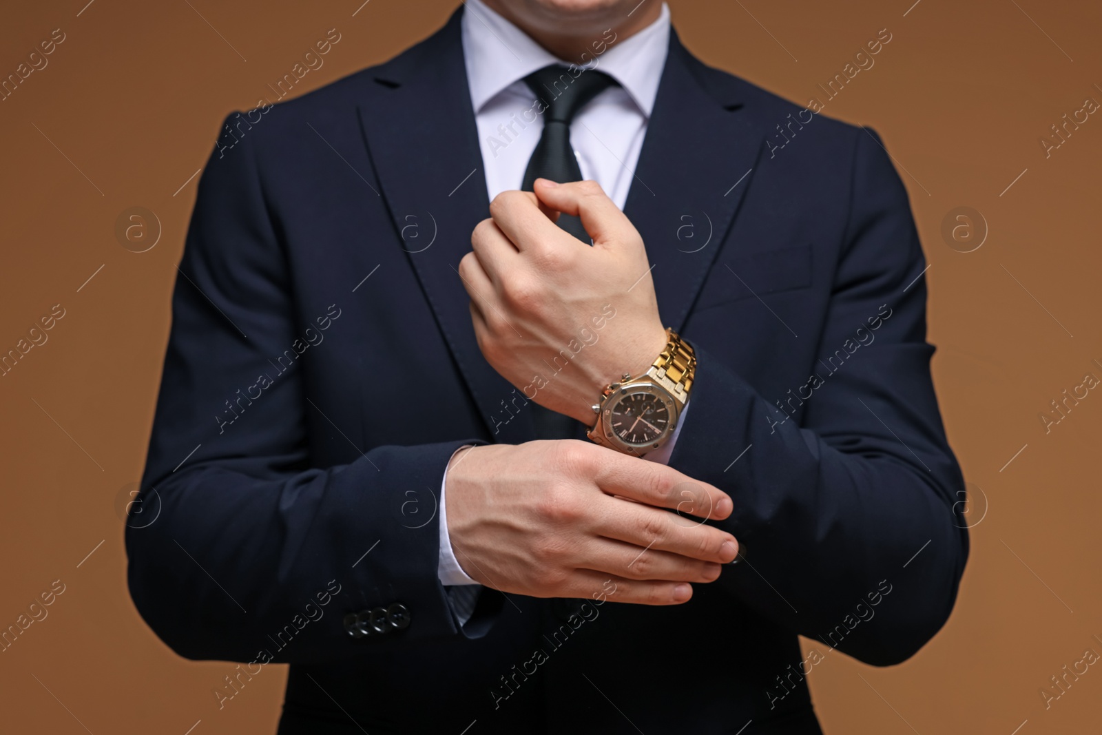 Photo of Man in classic suit with stylish watch on brown background, closeup