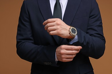 Photo of Man in classic suit with stylish watch on brown background, closeup