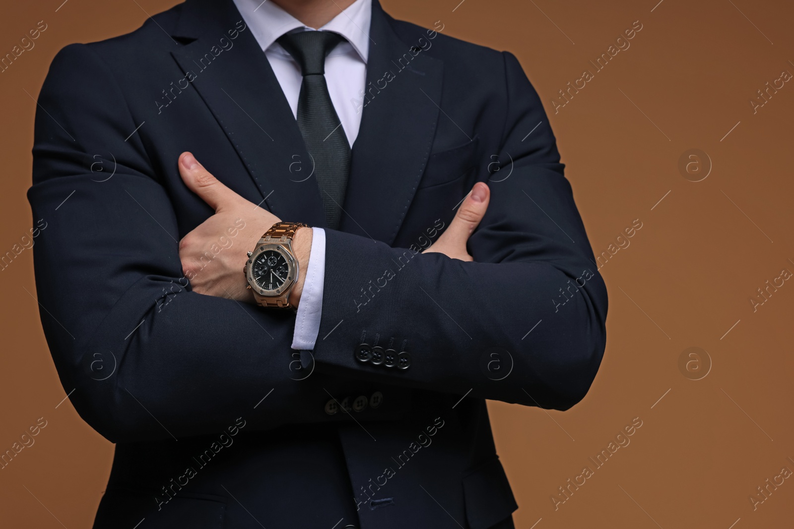 Photo of Man in classic suit with stylish watch on brown background, closeup