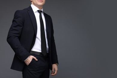 Photo of Man in classic suit on grey background, closeup. Space for text