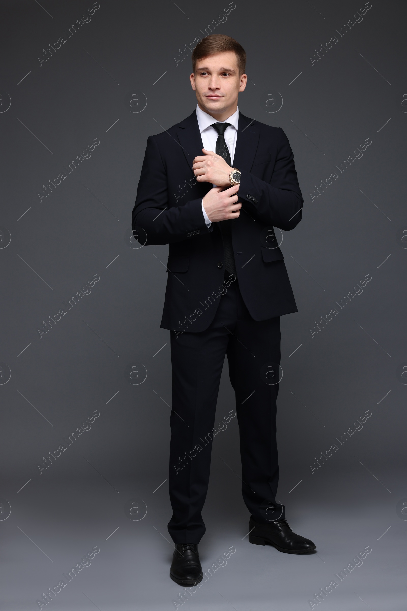 Photo of Man in classic suit with stylish watch on grey background