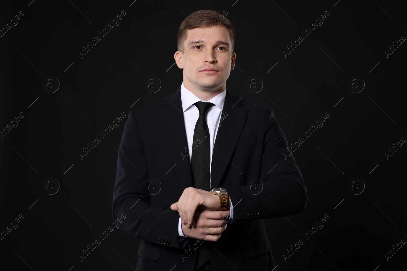 Photo of Man in classic suit with stylish watch on black background