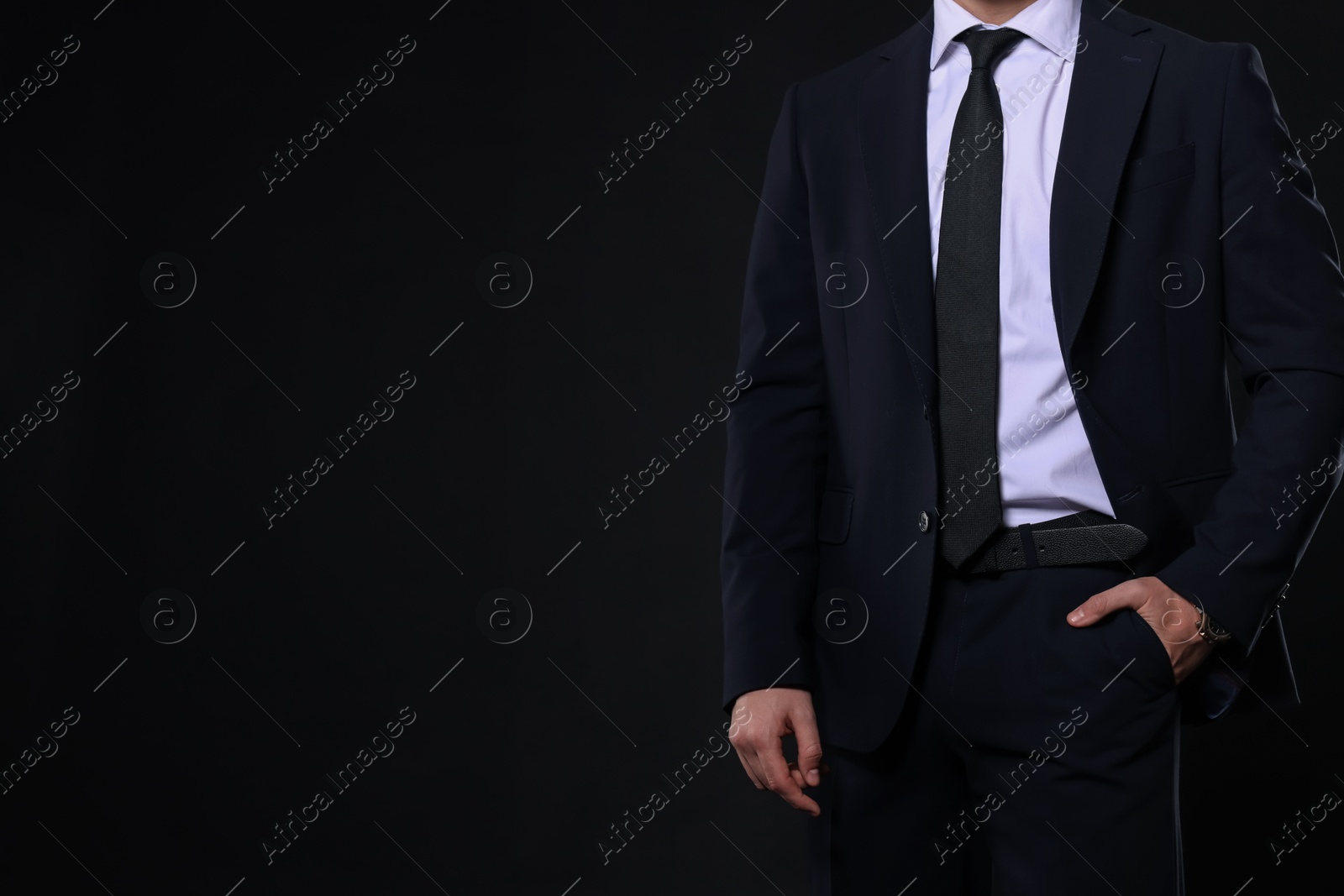 Photo of Man in classic suit on black background, closeup. Space for text