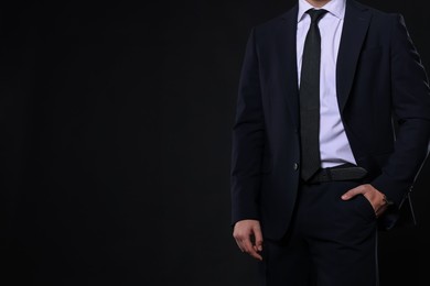 Photo of Man in classic suit on black background, closeup. Space for text