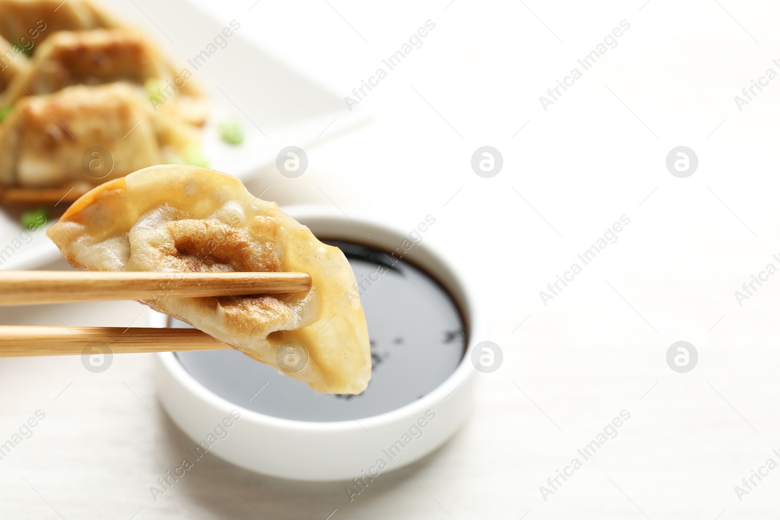 Photo of Eating fried gyoza dumplings at white table, closeup