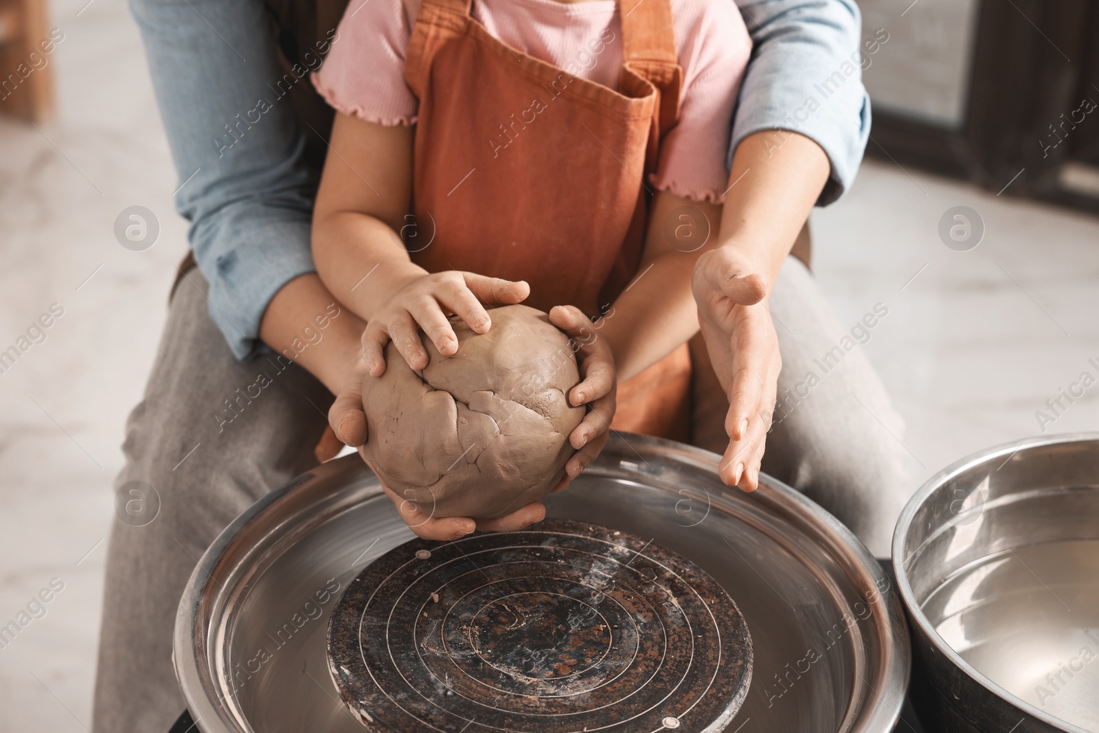 Photo of Hobby and craft. Mother with her daughter making pottery indoors, closeup