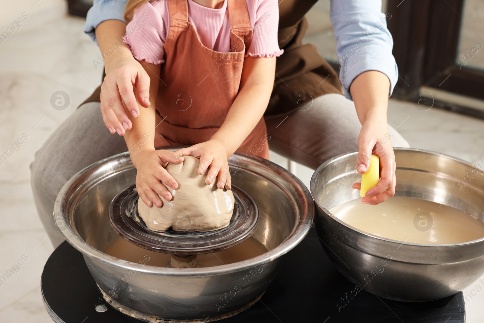 Photo of Hobby and craft. Mother with her daughter making pottery indoors, closeup