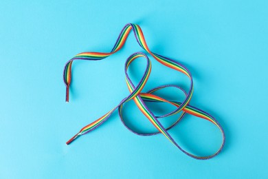 Photo of Shoelace in LGBT colors on light blue background, top view