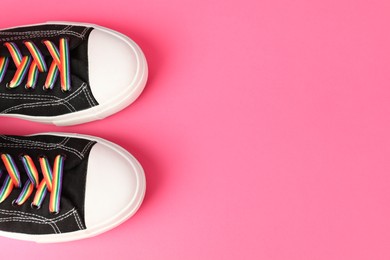 Photo of LGBT concept. Shoes with bright rainbow laces on pink background flat lay. Space for text