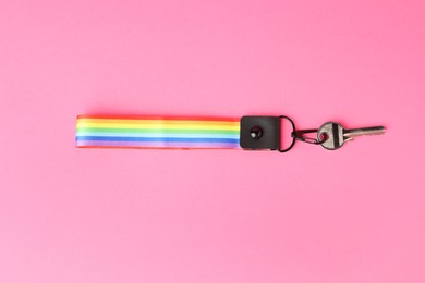 Photo of Key with keychain in LGBT colors on pink background, top view