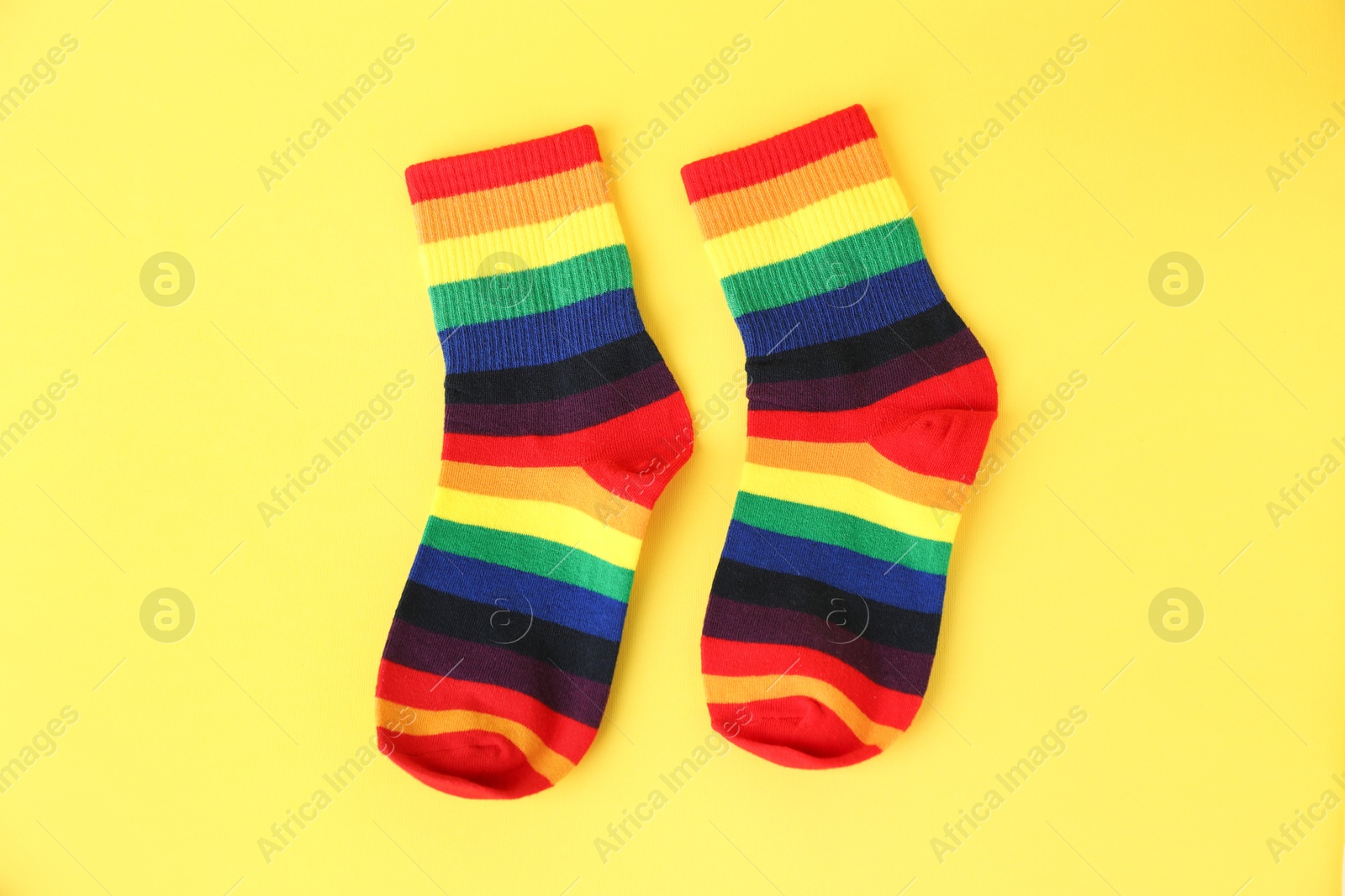 Photo of Pair of socks in LGBT colors on yellow background, flat lay