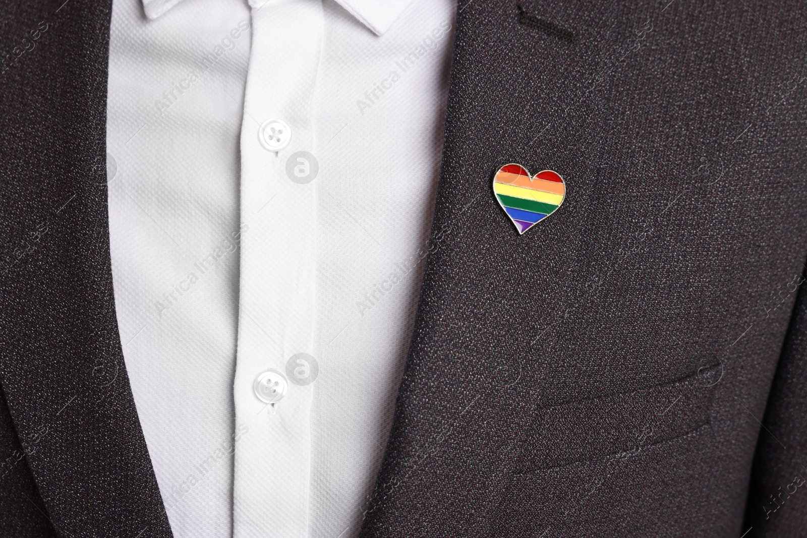 Photo of Man with heart shaped pin in colors of LGBT flag, closeup