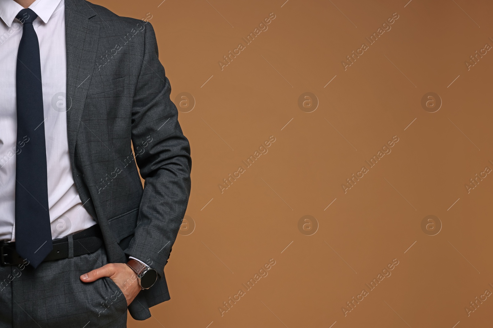 Photo of Man in classic suit on brown background, closeup. Space for text