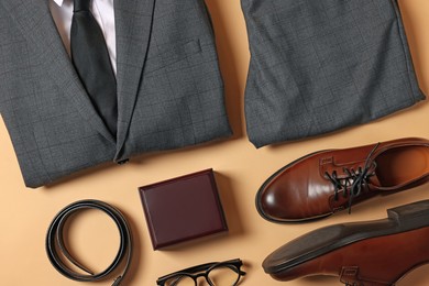 Photo of Elegant men's outfit. Stylish suit, accessories and shoes on beige background, flat lay