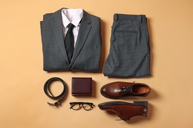 Photo of Elegant men's outfit. Stylish suit, accessories and shoes on beige background, flat lay