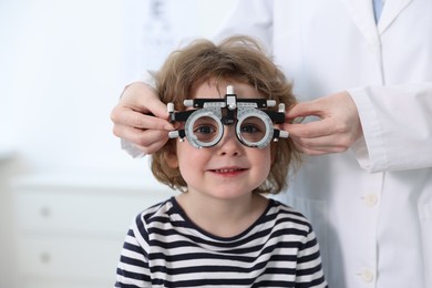 Photo of Ophthalmologist examining little boy's vision with trial frame in clinic, closeup