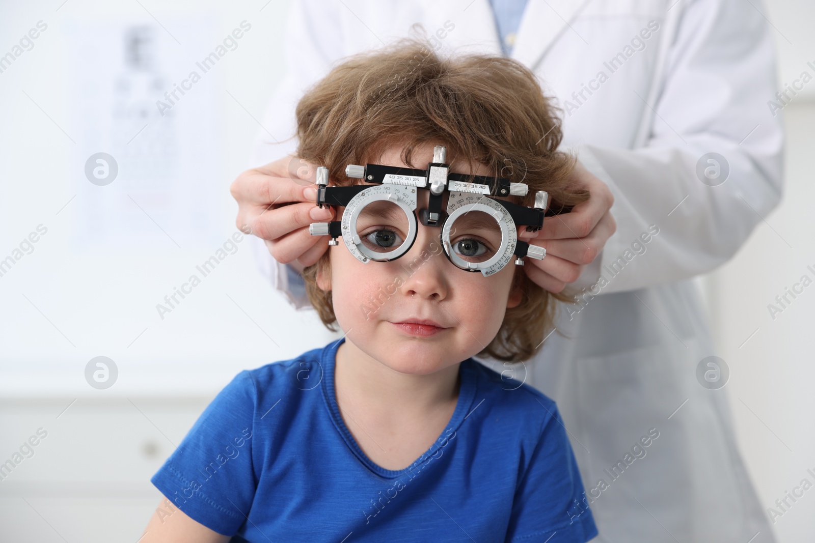 Photo of Ophthalmologist examining little boy's vision with trial frame in clinic, closeup