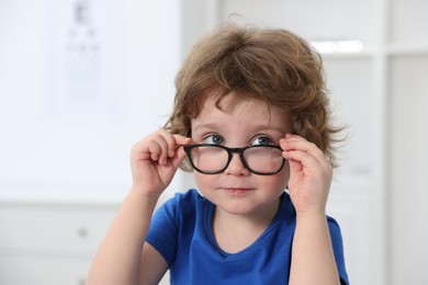 Photo of Little boy wearing glasses at ophthalmologist office