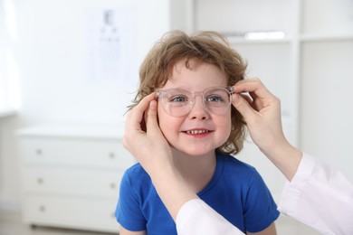 Vision testing. Ophthalmologist giving glasses to little boy in clinic, closeup