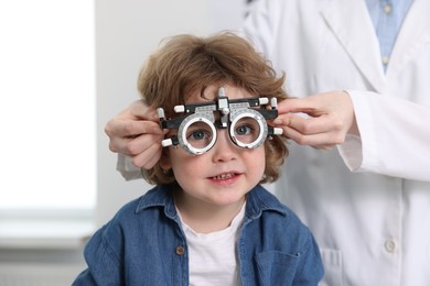 Photo of Ophthalmologist examining little boy's vision with trial frame in clinic, closeup