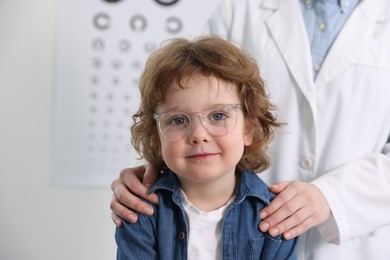 Little boy with glasses and ophthalmologist in office